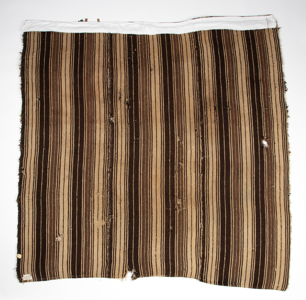 Håndlaget rye i ull, flossteknikk, Bunnen består av treskaftet kyper (stoff vevd med et mønster av skrå linjer), sydd sammen av tre bredder. Fargene er hvitt, sauesvart, brunt og brunmelert. Glattsiden er stripet på langs. På flossiden er det i den ene enden hvite og brune tverrstriper og et felt med brune ruter på hvit bunn (sjakkbrettruter). Mellom disse felt et brunmelert felt hvori initialer og årstall: "A S P  1816". Resten er brunmelert. Stoffdusker øverst i rød, blå og sauehvit ull.