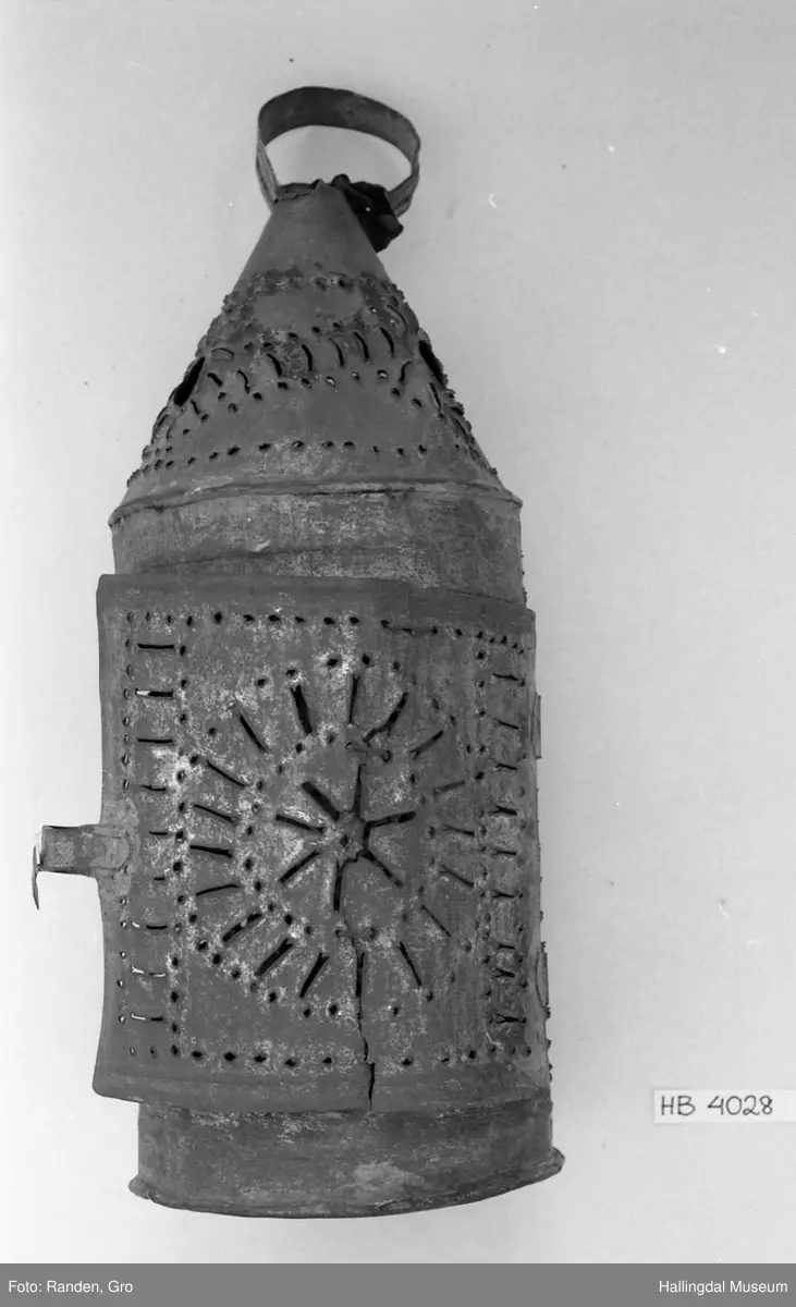 Fjøslykt, sylinder med kjegle i toppen. Lagd av metallblikk. Gjennomhullet.
