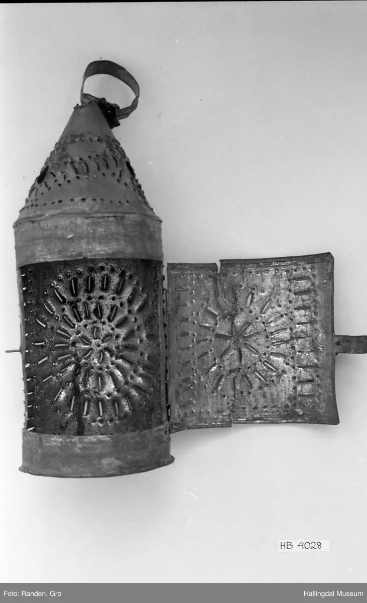 Fjøslykt, sylinder med kjegle i toppen. Lagd av metallblikk. Gjennomhullet.