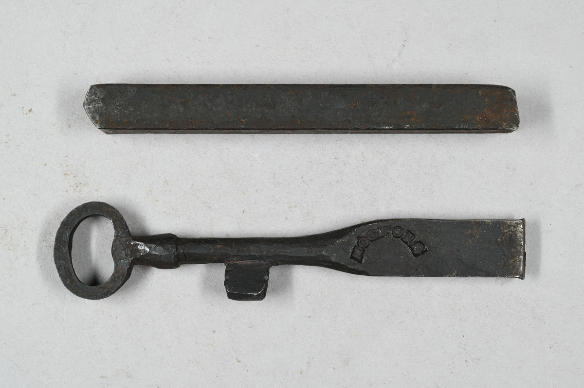 Två prover på nyckelämnen av järn. Märkning på ena provet med stämpel: "Högfors". Ett av proverna visar smidning av nyckelämne. Båda proverna från Högfors. Tillhörande lapp med samma notering.