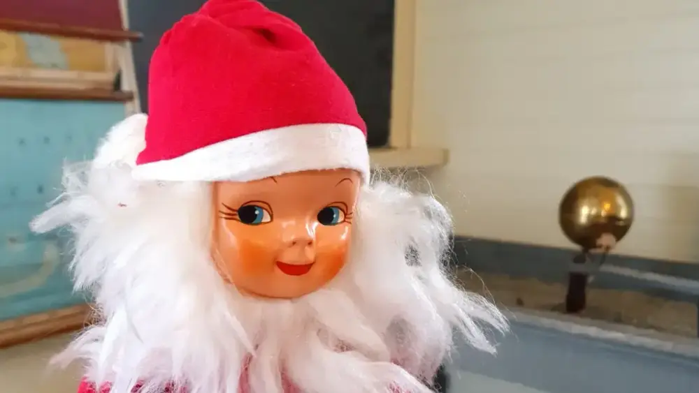 Nærbilde av smilende, søt gammel julenisse med sort hvitt skjegg