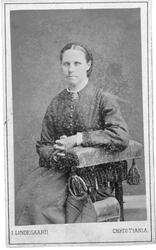 En kvinne med mørkt hår som er flettet og i mørk kneppet dra