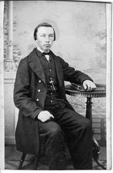 Portrett av en yngre mann som sitter ved et lite rundt bord.