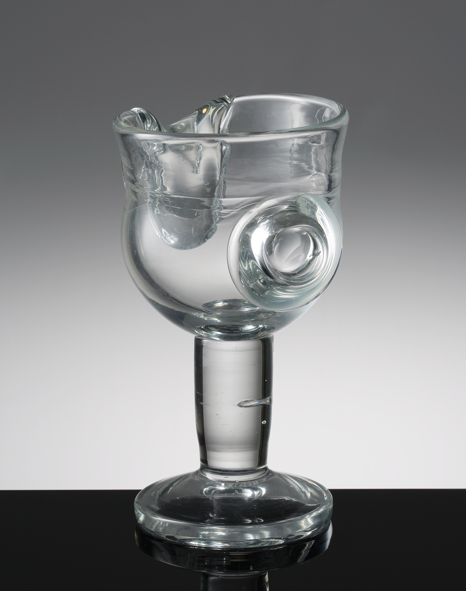 Driven pokal med tjockt cylindriskt ben med blåsa, påklipp som liknar en knapp och en tunga.