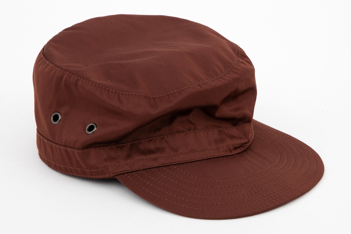 Høy kaps med stiv brem/skygge foran, såkalt "negl". Bremmen er avstivet innvendig, mellom ytterside og innside, og stukket med seks parallelle sømmer. Pullen er forsterket i nederkant med påsydd belegg utvendig, også det med stikninger. Innvendig et "svettebånd" av samme materiale, "vattert" og stukket. Pullen er sylindrisk og det innfelte toppstykket helt flatt. Hatten er ufôret og luftes gjennom to maljehull i hver side.