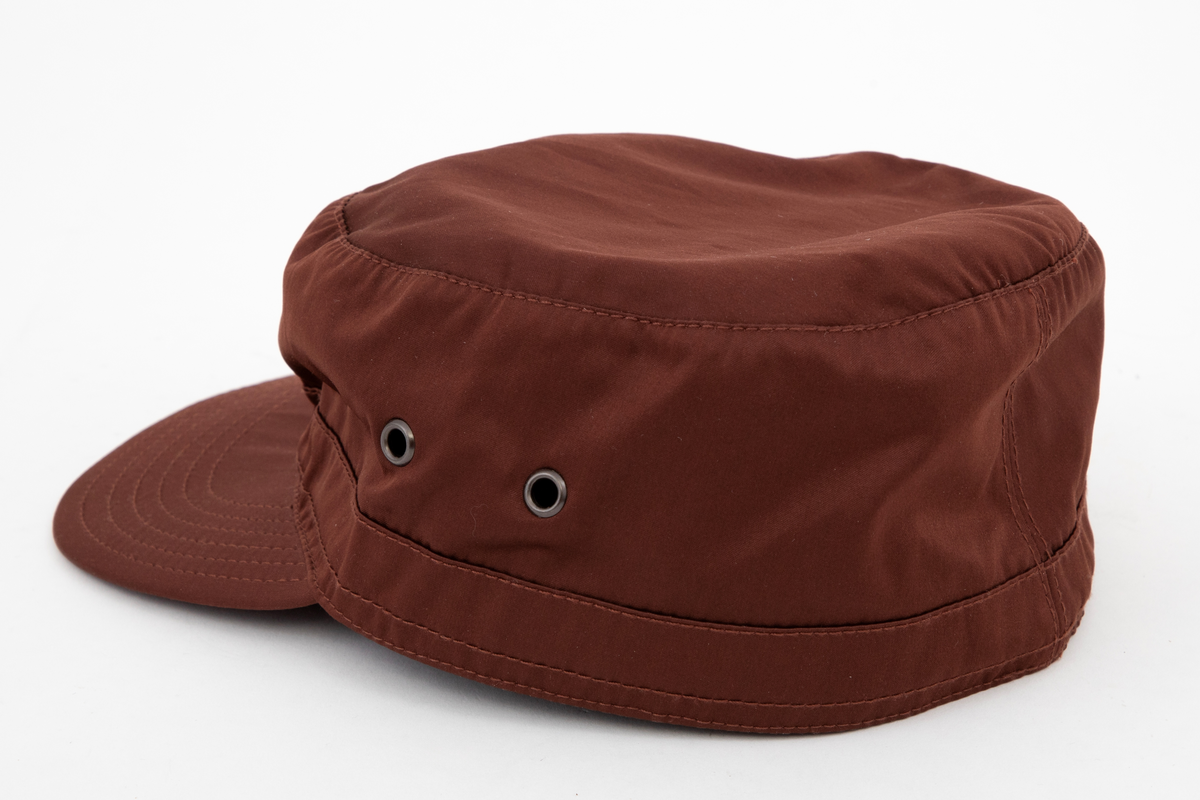 Høy kaps med stiv brem/skygge foran, såkalt "negl". Bremmen er avstivet innvendig, mellom ytterside og innside, og stukket med seks parallelle sømmer. Pullen er forsterket i nederkant med påsydd belegg utvendig, også det med stikninger. Innvendig et "svettebånd" av samme materiale, "vattert" og stukket. Pullen er sylindrisk og det innfelte toppstykket helt flatt. Hatten er ufôret og luftes gjennom to maljehull i hver side.