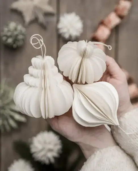 Två händer håller tre pappersfigurer i olika former.