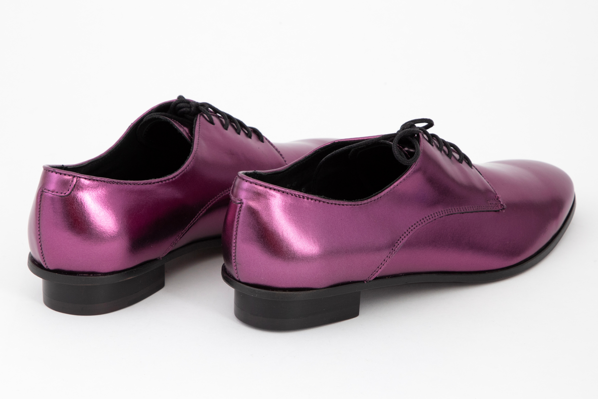 Herresko, metallisk rosa, avrundet foran med fem hull på hver side og rund svart lisse. Lav hæl med svart kant rundt skoen.