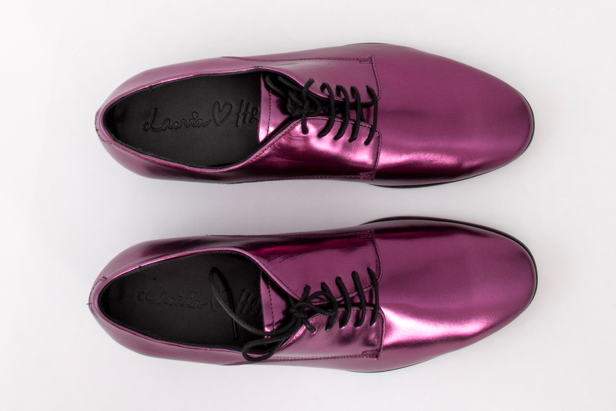 Herresko, metallisk rosa, avrundet foran med fem hull på hver side og rund svart lisse. Lav hæl med svart kant rundt skoen.