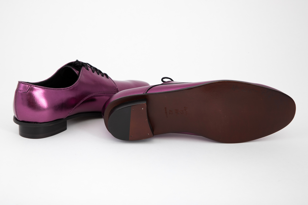 Herresko, metallisk rosa, avrundet foran med fem hull på hver side og rund svart lisse. Lav hæl med svart kant rundt skoen.