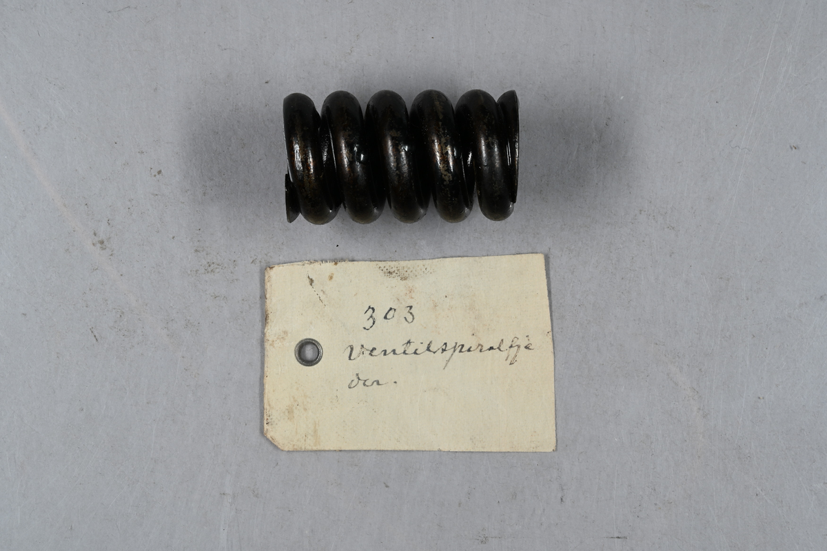 Sju prover på ventilspiralfjäder i olika storlekar. Sex av proverna även märkt med egen etikett med märkning 303-308. Tillhörande lapp med notering: "Diverse ventilspiralfjädrar för explosionsmotorer. Från A-B. Spiralfabriken."