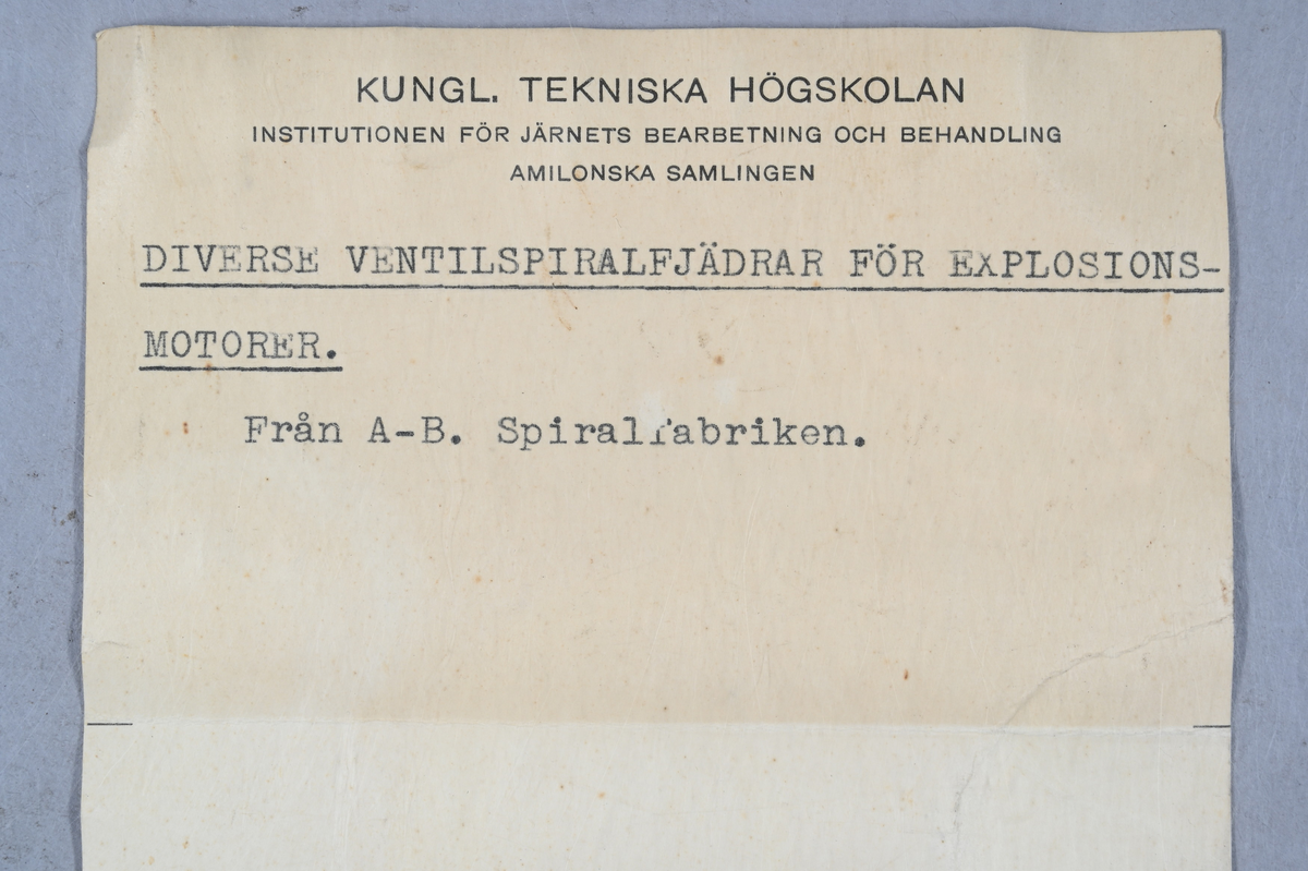 Sju prover på ventilspiralfjäder i olika storlekar. Sex av proverna även märkt med egen etikett med märkning 303-308. Tillhörande lapp med notering: "Diverse ventilspiralfjädrar för explosionsmotorer. Från A-B. Spiralfabriken."