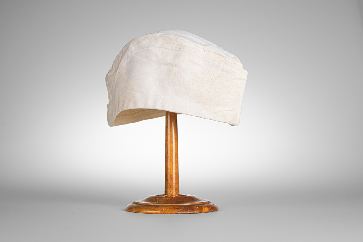 Vii, avlång mössa i bomullstyg. Stämpel med texten "KRONOBAGERIET" på båda sidorna inuti mössan. Märkt med etikett och texten "Fristads S C 58 -SANFORD" i blå text.