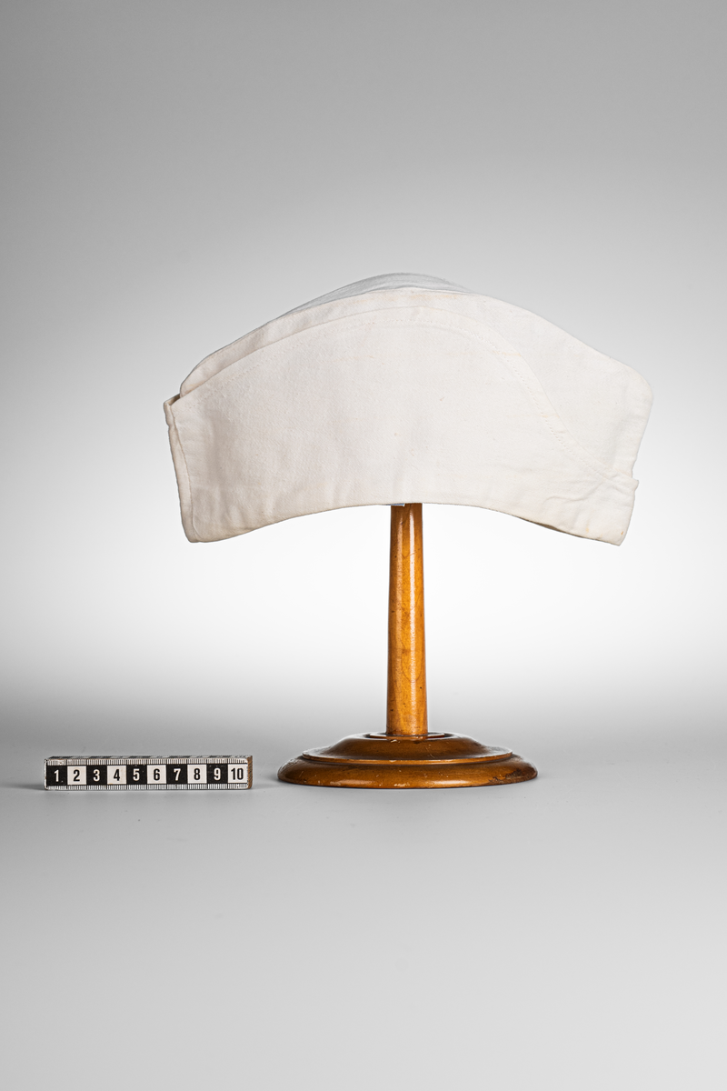 Vii, avlång mössa i bomullstyg. Stämpel med texten "KRONOBAGERIET" på båda sidorna inuti mössan. Märkt med etikett och texten "Fristads S C 58 -SANFORD" i blå text.