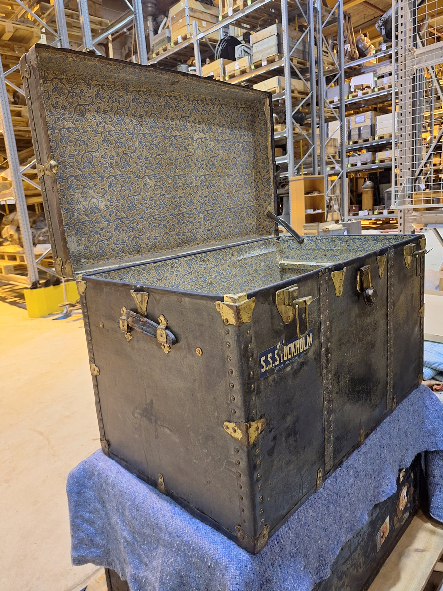 Koffert. 
Fodrad med blåblommig papp på beige botten. Fläckad i botten. Två trälister längs kortsidan ca 100 mm från locket.