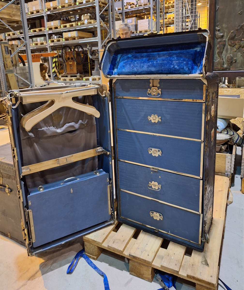 Inredd koffert som tillhört postorderkungen Oscar Ahrén (1881-1948). Kofferten är inredd med galghängare och lådor. På utsidan klistermärken från olika delar av världen.