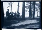 Leonarth Morthensen och sönerna sitter vid ett picknick-bord och fikar, utomhus vid vattnet.