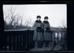 Systrarna Elsa och Gudrun i likadana ytterkläder, porträtterade på balkongen till familjen Morthensens villa Solveden, Djursholm.