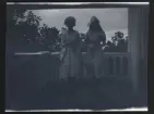 Två flickor, Gudrun och Elsa, utklädda. Porträtterade på balkongen till familjen Morthensens villa Solveden, Djursholm.