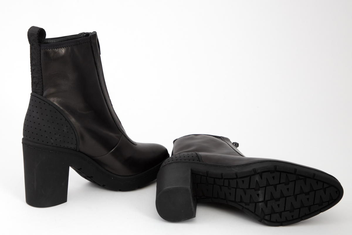 Ankelhøye damestøvletter i svart skinn med kraftig, svart glidelås midt foran. På baksiden påsydd bånd med hempe øverst og innvevd logo: WANG. Kraftig, kantete hæl og profilert såle med bokstavene WA etter hverandre.