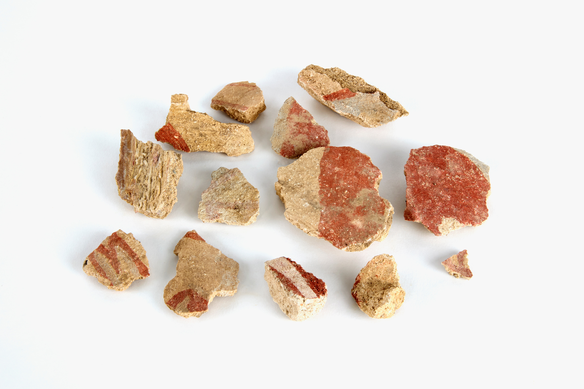 En samling av fragment av målad puts och bruk med kalkputs och bemålning. 17 fyndaskar med fragment i olika storlekar.

Fyndask 1: Totalt 13 fragment med röd och vit färg, en ser ut att ha träavtryck (varit fäst mot ett trästycke).

Fyndask 2: Totalt 7 fragment alla utom en har röd och vit färg, endast en med gråaktig obehandlad puts. 

Fyndask 3: Totalt 1 större fragment med röd och vit färg på enda sidan.

Fyndask 4: Totalt 4 fragment alla utom en med röd och vit färg, endast en med vit puts. 

Fyndask 5: Totalt 3 fragment med röd och vit färg, varav en är sotig. 

Fyndask 6: Totalt 3 fragment med röd och vit färg, en mycket tydlig medan de andra två mer diffusa. 

Fyndask 7:  Totalt 27 fragment, 24 av dessa är bemålade med röd och vit färg, 3  fragment med gråaktig obehandlad puts. 

Fyndask 8: Totalt 5 fragment, varav 4 större och en mycket liten. Alla större fragment med olika karaktär. En med vit kalkbruk och utan putsad yta, en annan med svart och röd putsad yta. Det tredje fragmentet har lite rödfärgad puts bevarad och på andra sidan ser det ut att ha träavtryck (varit fäst mot ett trästycke). Det fjärde fragmentet har en mer brungrå nyans. I fyndasken låg en lapp med text N. om V. portalen. 

Fyndask 9: Totalt 13 fragment, varav ett större fragment med svart och rödmålad puts. Ett annat fragment med svart och vitmålad puts, det tredje fragmentet har endast svartmålad puts. Sedan finns tre rödmålande putsfragment, samt tre fragment med röda linjer. Fyra fragment är ytterst små och intetsägande.

Fyndask 10: Totalt 9 fragment samt smådelar varav två har rött färgfragment. Det största fragmentet samt fyra andra är svart- och rödmålat. Tre putsfragment har röda linjer.
 
Fyndask 11: Totalt 1 fragment med röda linjer samt en mindre del med blågråa linjer. 

Fyndask 12: Totalt 1 fragment med blågrå rundad linje samt samt en mindre punkt eller koncentration nedanför.  

Fyndask 13: Totalt 5 fragment varav två med rödmålad puts. De andra tre har linjer. 

Fyndask 14: Totalt 1 fragment med vit och rödmålad puts, med flertal linjer som eventuellt kan vara del av en bokstav.
 
Fyndask 15: Totalt 1 fragment med vit och svartmålad puts, med flertal linjer som eventuellt kan vara del av en större figur. Ena delen syns en större koncentration som skulle kunna vara en fågel. 

Fyndask 16: Totalt 1 fragment med vit och rödmålad puts, med flertal rundade linjer som eventuellt kan vara del av växtlig dekor.

Fyndask 17: Totalt 1 fragment med rödmålad puts, med en vit linje.