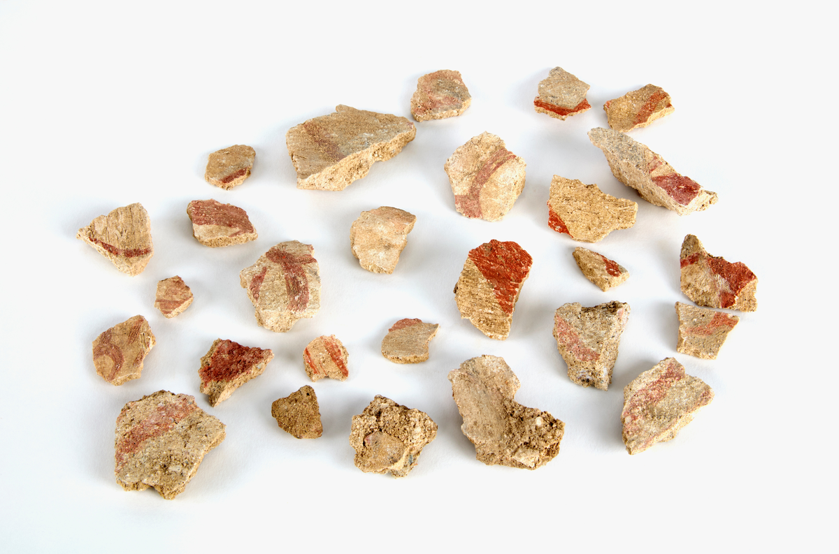 En samling av fragment av målad puts och bruk med kalkputs och bemålning. 17 fyndaskar med fragment i olika storlekar.

Fyndask 1: Totalt 13 fragment med röd och vit färg, en ser ut att ha träavtryck (varit fäst mot ett trästycke).

Fyndask 2: Totalt 7 fragment alla utom en har röd och vit färg, endast en med gråaktig obehandlad puts. 

Fyndask 3: Totalt 1 större fragment med röd och vit färg på enda sidan.

Fyndask 4: Totalt 4 fragment alla utom en med röd och vit färg, endast en med vit puts. 

Fyndask 5: Totalt 3 fragment med röd och vit färg, varav en är sotig. 

Fyndask 6: Totalt 3 fragment med röd och vit färg, en mycket tydlig medan de andra två mer diffusa. 

Fyndask 7:  Totalt 27 fragment, 24 av dessa är bemålade med röd och vit färg, 3  fragment med gråaktig obehandlad puts. 

Fyndask 8: Totalt 5 fragment, varav 4 större och en mycket liten. Alla större fragment med olika karaktär. En med vit kalkbruk och utan putsad yta, en annan med svart och röd putsad yta. Det tredje fragmentet har lite rödfärgad puts bevarad och på andra sidan ser det ut att ha träavtryck (varit fäst mot ett trästycke). Det fjärde fragmentet har en mer brungrå nyans. I fyndasken låg en lapp med text N. om V. portalen. 

Fyndask 9: Totalt 13 fragment, varav ett större fragment med svart och rödmålad puts. Ett annat fragment med svart och vitmålad puts, det tredje fragmentet har endast svartmålad puts. Sedan finns tre rödmålande putsfragment, samt tre fragment med röda linjer. Fyra fragment är ytterst små och intetsägande.

Fyndask 10: Totalt 9 fragment samt smådelar varav två har rött färgfragment. Det största fragmentet samt fyra andra är svart- och rödmålat. Tre putsfragment har röda linjer.
 
Fyndask 11: Totalt 1 fragment med röda linjer samt en mindre del med blågråa linjer. 

Fyndask 12: Totalt 1 fragment med blågrå rundad linje samt samt en mindre punkt eller koncentration nedanför.  

Fyndask 13: Totalt 5 fragment varav två med rödmålad puts. De andra tre har linjer. 

Fyndask 14: Totalt 1 fragment med vit och rödmålad puts, med flertal linjer som eventuellt kan vara del av en bokstav.
 
Fyndask 15: Totalt 1 fragment med vit och svartmålad puts, med flertal linjer som eventuellt kan vara del av en större figur. Ena delen syns en större koncentration som skulle kunna vara en fågel. 

Fyndask 16: Totalt 1 fragment med vit och rödmålad puts, med flertal rundade linjer som eventuellt kan vara del av växtlig dekor.

Fyndask 17: Totalt 1 fragment med rödmålad puts, med en vit linje.