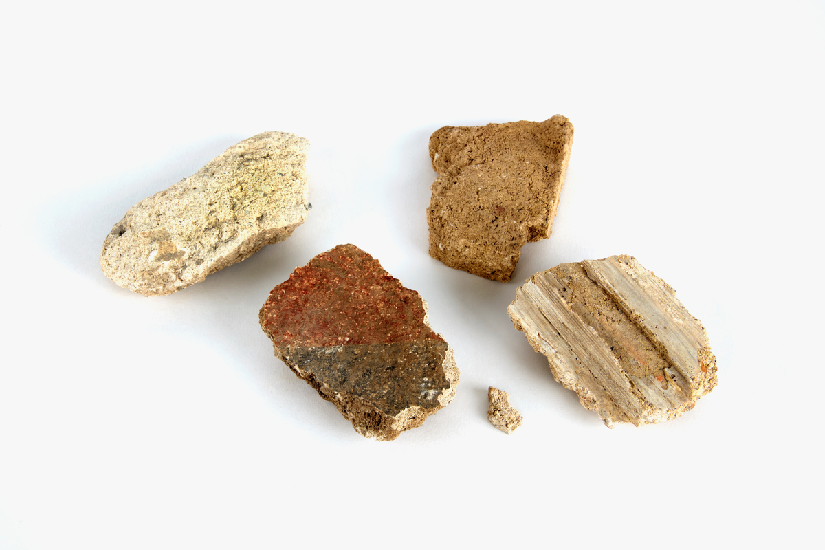 En samling av fragment av målad puts och bruk med kalkputs och bemålning. 17 fyndaskar med fragment i olika storlekar.

Fyndask 1: Totalt 13 fragment med röd och vit färg, en ser ut att ha träavtryck (varit fäst mot ett trästycke).

Fyndask 2: Totalt 7 fragment alla utom en har röd och vit färg, endast en med gråaktig obehandlad puts. 

Fyndask 3: Totalt 1 större fragment med röd och vit färg på enda sidan.

Fyndask 4: Totalt 4 fragment alla utom en med röd och vit färg, endast en med vit puts. 

Fyndask 5: Totalt 3 fragment med röd och vit färg, varav en är sotig. 

Fyndask 6: Totalt 3 fragment med röd och vit färg, en mycket tydlig medan de andra två mer diffusa. 

Fyndask 7:  Totalt 27 fragment, 24 av dessa är bemålade med röd och vit färg, 3  fragment med gråaktig obehandlad puts. 

Fyndask 8: Totalt 5 fragment, varav 4 större och en mycket liten. Alla större fragment med olika karaktär. En med vit kalkbruk och utan putsad yta, en annan med svart och röd putsad yta. Det tredje fragmentet har lite rödfärgad puts bevarad och på andra sidan ser det ut att ha träavtryck (varit fäst mot ett trästycke). Det fjärde fragmentet har en mer brungrå nyans. I fyndasken låg en lapp med text N. om V. portalen. 

Fyndask 9: Totalt 13 fragment, varav ett större fragment med svart och rödmålad puts. Ett annat fragment med svart och vitmålad puts, det tredje fragmentet har endast svartmålad puts. Sedan finns tre rödmålande putsfragment, samt tre fragment med röda linjer. Fyra fragment är ytterst små och intetsägande.

Fyndask 10: Totalt 9 fragment samt smådelar varav två har rött färgfragment. Det största fragmentet samt fyra andra är svart- och rödmålat. Tre putsfragment har röda linjer.
 
Fyndask 11: Totalt 1 fragment med röda linjer samt en mindre del med blågråa linjer. 

Fyndask 12: Totalt 1 fragment med blågrå rundad linje samt samt en mindre punkt eller koncentration nedanför.  

Fyndask 13: Totalt 5 fragment varav två med rödmålad puts. De andra tre har linjer. 

Fyndask 14: Totalt 1 fragment med vit och rödmålad puts, med flertal linjer som eventuellt kan vara del av en bokstav.
 
Fyndask 15: Totalt 1 fragment med vit och svartmålad puts, med flertal linjer som eventuellt kan vara del av en större figur. Ena delen syns en större koncentration som skulle kunna vara en fågel. 

Fyndask 16: Totalt 1 fragment med vit och rödmålad puts, med flertal rundade linjer som eventuellt kan vara del av växtlig dekor.

Fyndask 17: Totalt 1 fragment med rödmålad puts, med en vit linje.