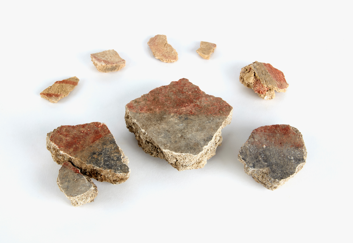 En samling av fragment av målad puts och bruk med kalkputs och bemålning. 17 fyndaskar med fragment i olika storlekar.

Fyndask 1: Totalt 13 fragment med röd och vit färg, en ser ut att ha träavtryck (varit fäst mot ett trästycke).

Fyndask 2: Totalt 7 fragment alla utom en har röd och vit färg, endast en med gråaktig obehandlad puts. 

Fyndask 3: Totalt 1 större fragment med röd och vit färg på enda sidan.

Fyndask 4: Totalt 4 fragment alla utom en med röd och vit färg, endast en med vit puts. 

Fyndask 5: Totalt 3 fragment med röd och vit färg, varav en är sotig. 

Fyndask 6: Totalt 3 fragment med röd och vit färg, en mycket tydlig medan de andra två mer diffusa. 

Fyndask 7:  Totalt 27 fragment, 24 av dessa är bemålade med röd och vit färg, 3  fragment med gråaktig obehandlad puts. 

Fyndask 8: Totalt 5 fragment, varav 4 större och en mycket liten. Alla större fragment med olika karaktär. En med vit kalkbruk och utan putsad yta, en annan med svart och röd putsad yta. Det tredje fragmentet har lite rödfärgad puts bevarad och på andra sidan ser det ut att ha träavtryck (varit fäst mot ett trästycke). Det fjärde fragmentet har en mer brungrå nyans. I fyndasken låg en lapp med text N. om V. portalen. 

Fyndask 9: Totalt 13 fragment, varav ett större fragment med svart och rödmålad puts. Ett annat fragment med svart och vitmålad puts, det tredje fragmentet har endast svartmålad puts. Sedan finns tre rödmålande putsfragment, samt tre fragment med röda linjer. Fyra fragment är ytterst små och intetsägande.

Fyndask 10: Totalt 9 fragment samt smådelar varav två har rött färgfragment. Det största fragmentet samt fyra andra är svart- och rödmålat. Tre putsfragment har röda linjer.
 
Fyndask 11: Totalt 1 fragment med röda linjer samt en mindre del med blågråa linjer. 

Fyndask 12: Totalt 1 fragment med blågrå rundad linje samt samt en mindre punkt eller koncentration nedanför.  

Fyndask 13: Totalt 5 fragment varav två med rödmålad puts. De andra tre har linjer. 

Fyndask 14: Totalt 1 fragment med vit och rödmålad puts, med flertal linjer som eventuellt kan vara del av en bokstav.
 
Fyndask 15: Totalt 1 fragment med vit och svartmålad puts, med flertal linjer som eventuellt kan vara del av en större figur. Ena delen syns en större koncentration som skulle kunna vara en fågel. 

Fyndask 16: Totalt 1 fragment med vit och rödmålad puts, med flertal rundade linjer som eventuellt kan vara del av växtlig dekor.

Fyndask 17: Totalt 1 fragment med rödmålad puts, med en vit linje.