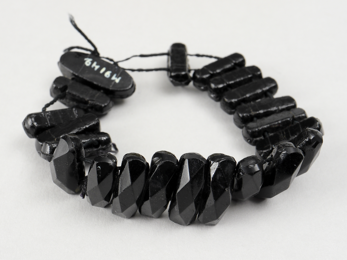 Armband och smyckesdelar/pärlor av stenkol.
Inskrivet i huvudbok 1936.