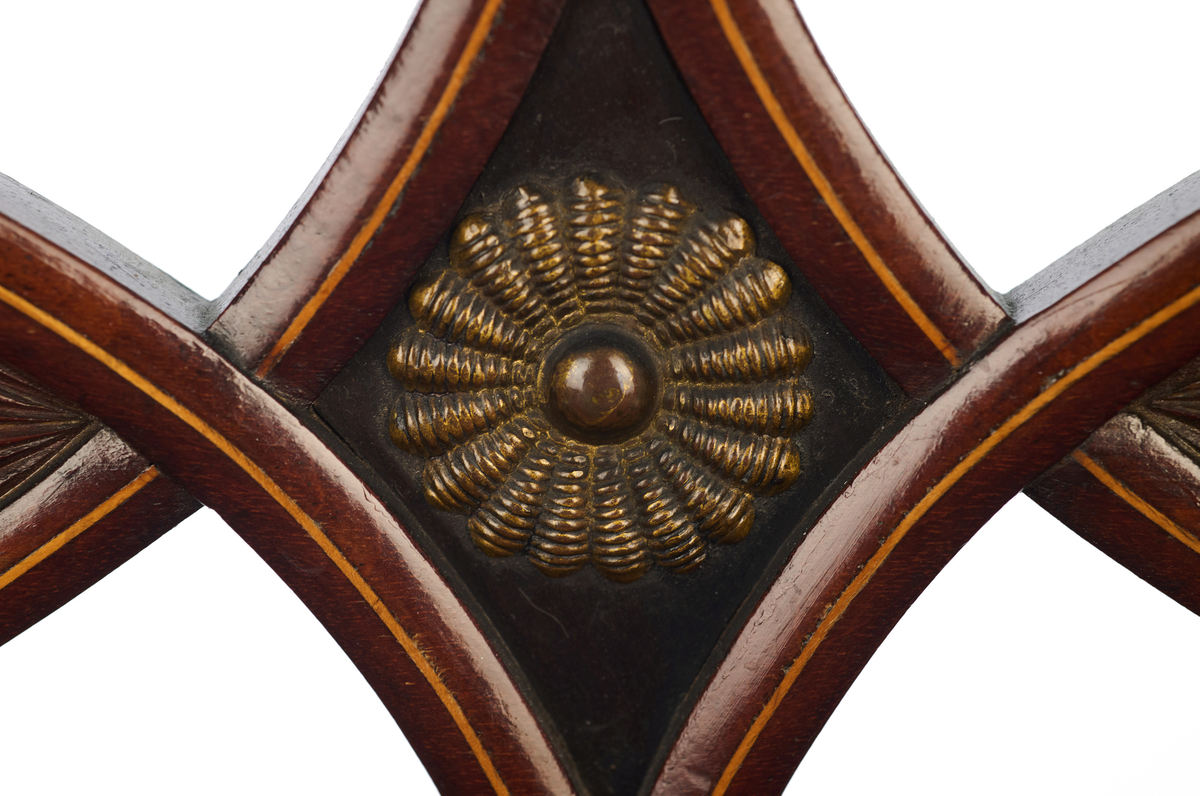 Stol av finért mahogni, som hviler på fire ben. Åpen rygg med glatt buet toppstykke med intarsia i lyst tre. Gjennombrutt tverrspross med halvsirkelformede ornamenter, hvor det ovale midtpartiet er markert med en riflet metallrosett. Kurvede akterstaver glir over i bakbenene, mens forbenene er dreide. Trapesformet sete med sekundært blåfarget trekk i ull. Mykt buet sarg, hvis sider er svakt trukket inn under setet.
