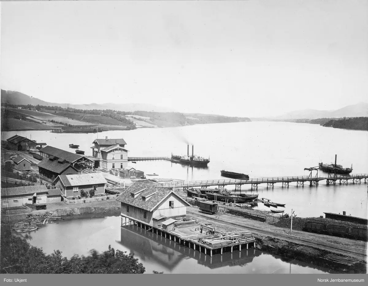 Oversiktsbilde med Eidsvoll stasjon, to dampbåter, beddingen med to klinkbygde lektere og brua over Vorma