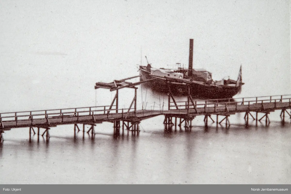 Oversiktsbilde med Eidsvoll stasjon, to dampbåter, beddingen med to klinkbygde lektere og brua over Vorma