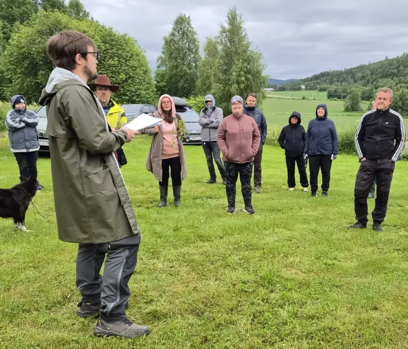En person håller en guidning för en samling människor, utomhus