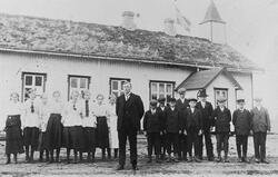 Klassebilde, skolen bak de oppstilte elevene i uniform, lære