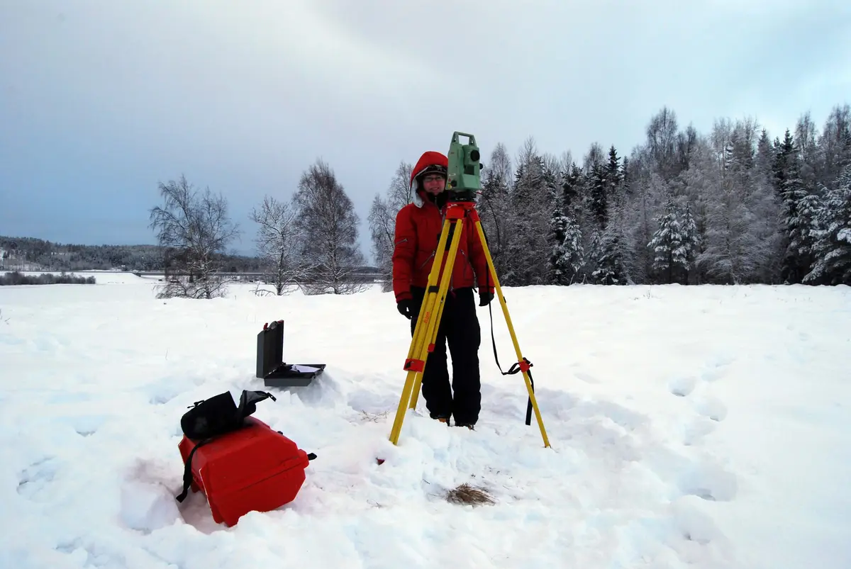 Person och totalstation i snölandskap