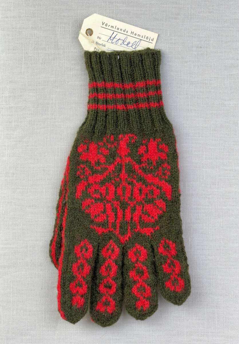 En stickad fingervante, med randig mudd i 2-2 resår (2 räta och 2 aviga maskor) och mönsterstickad vante i slätstickning, av 2-trådigt ullgarn.