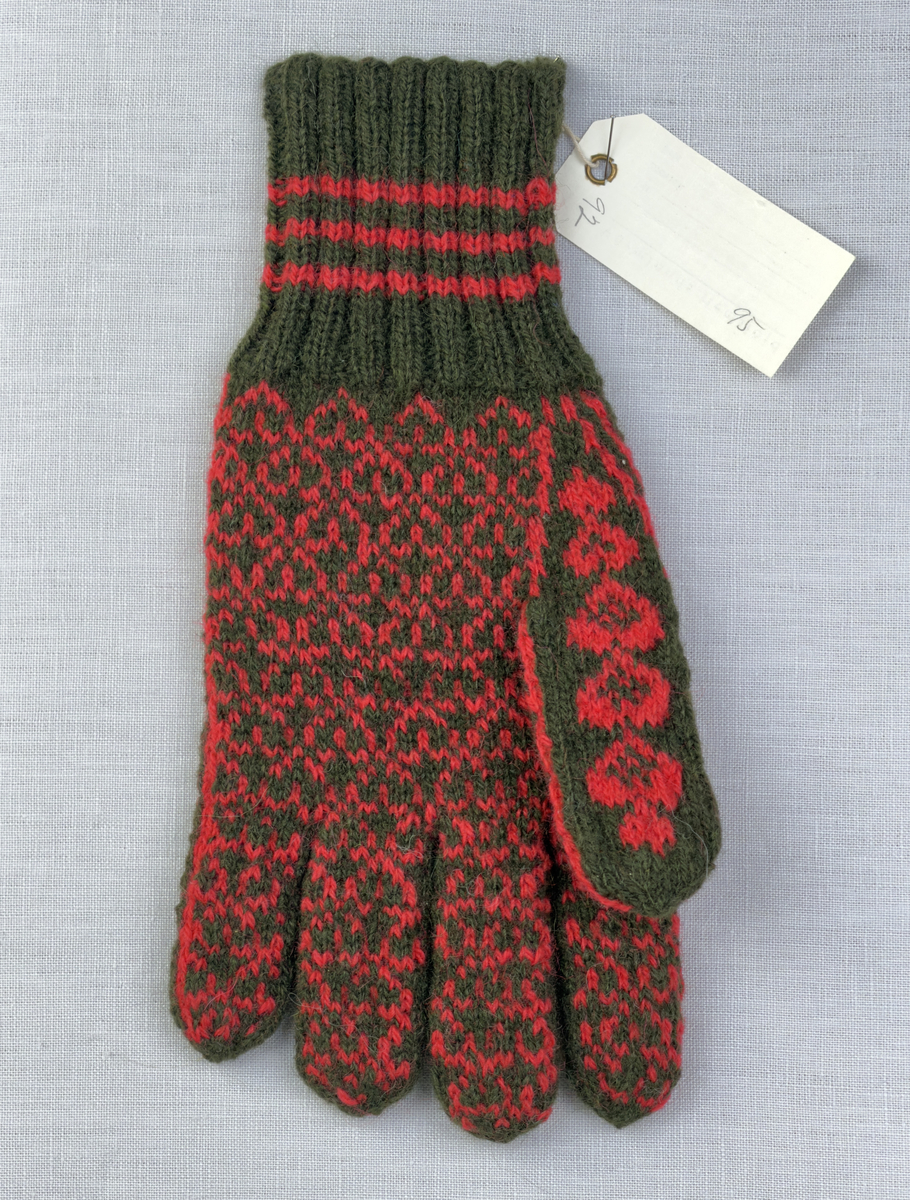 En stickad fingervante, med randig mudd i 2-2 resår (2 räta och 2 aviga maskor) och mönsterstickad vante i slätstickning, av 2-trådigt ullgarn.