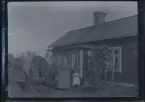 En familj med två små barn fotograferade framför sitt hus, tillsammans med sin häst. Det yngsta barnet sitter uppe på hästryggen.