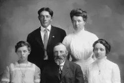 Portrett av en en (familie?)gruppe. Midt foran sitter en eld