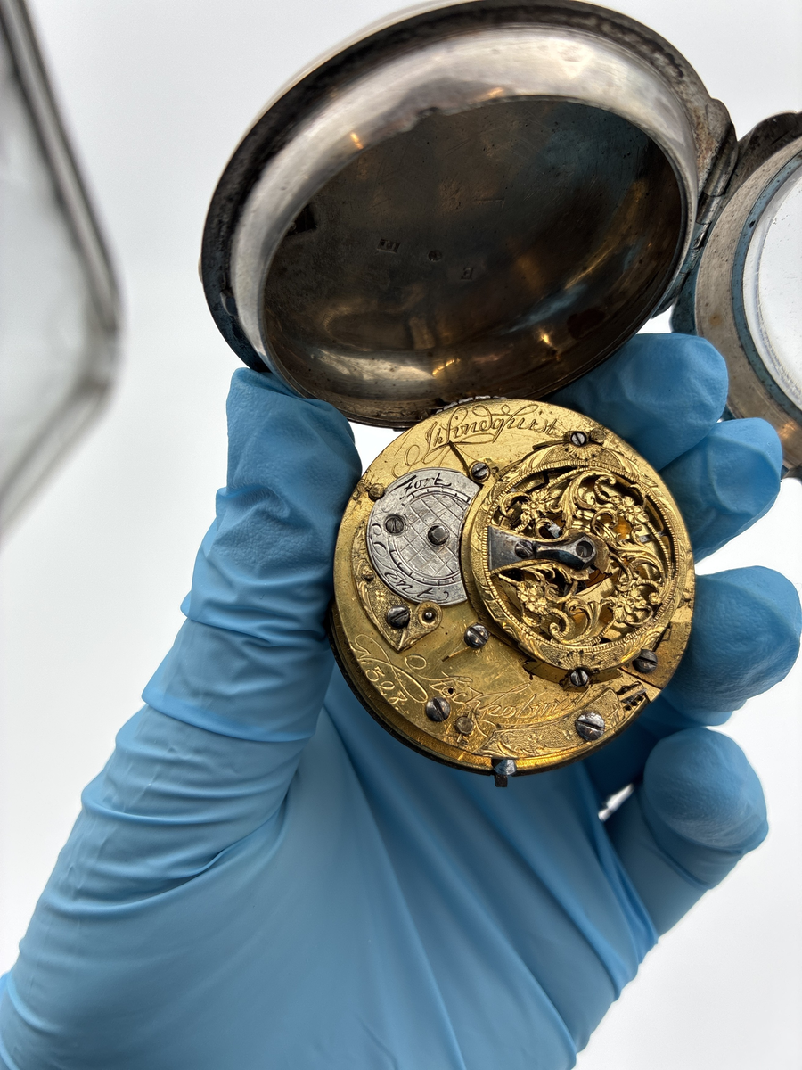 Fickur med urtavla av vit emalj med romerska siffror för timmar och arabiska siffror för minuter. Även signerat Lindquist Stockholm i svart. Urverket signerat "Jh Lindquist Stockholm N: 328" och avser hovurmakare Johan Lindquist (1728-1779). 

Boett av silver med stämplar: 
Mästarstämpel: IL = Johan Lindqvist 
Årsbokstav: E = 1763
Kattfot/tre kronor