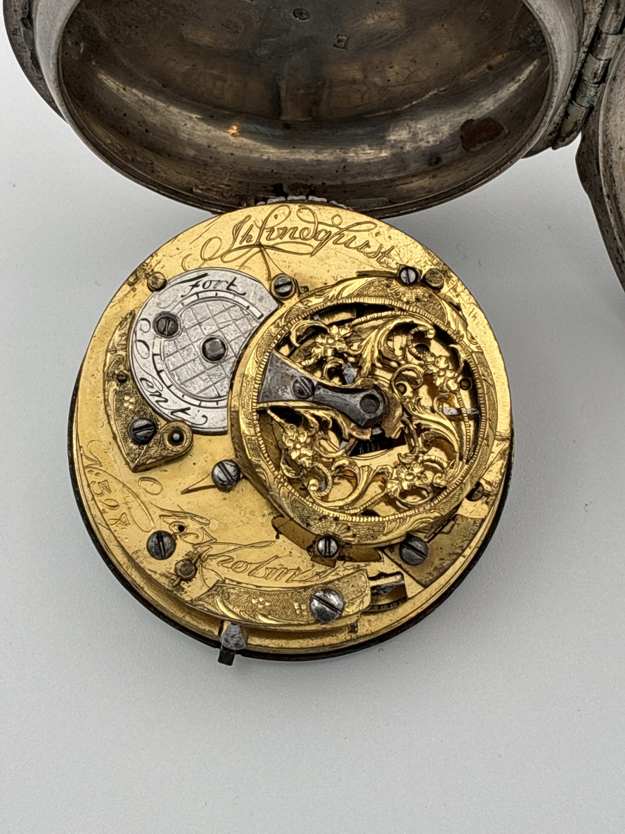 Fickur med urtavla av vit emalj med romerska siffror för timmar och arabiska siffror för minuter. Även signerat Lindquist Stockholm i svart. Urverket signerat "Jh Lindquist Stockholm N: 328" och avser hovurmakare Johan Lindquist (1728-1779). 

Boett av silver med stämplar: 
Mästarstämpel: IL = Johan Lindqvist 
Årsbokstav: E = 1763
Kattfot/tre kronor