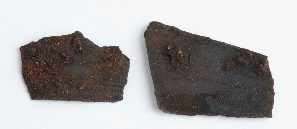 Två små, tunna järnbleck. Ett av dem är ornerat med tre parallella lunjer.
Storlek: 17x14 mm, 15x11 mm.
Det saknade fragmentet är 12x7 mm enligt fyndanteckningarna.