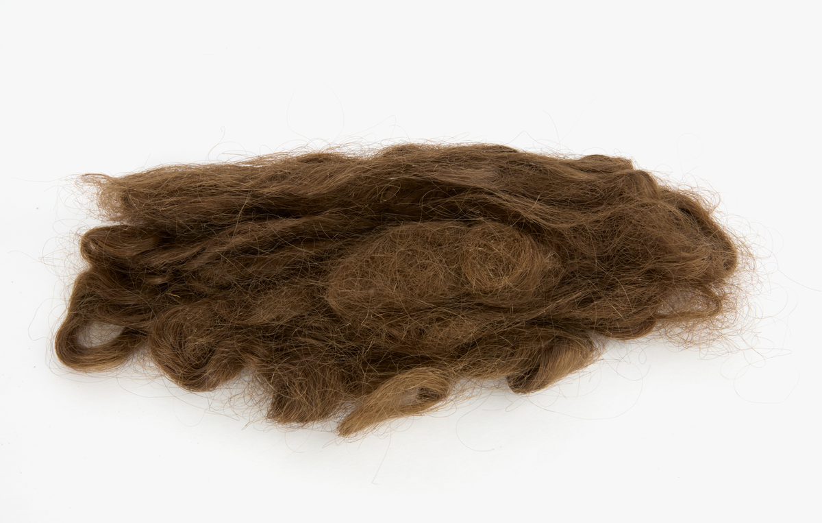 Löshår, brunt, som kan ha använts vid håruppsättningar alternativt hår till försäljning.