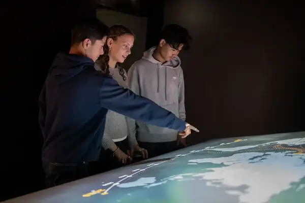 Elever peker på interaktiv videoinstallasjon med et verdenskart og en tidslinje