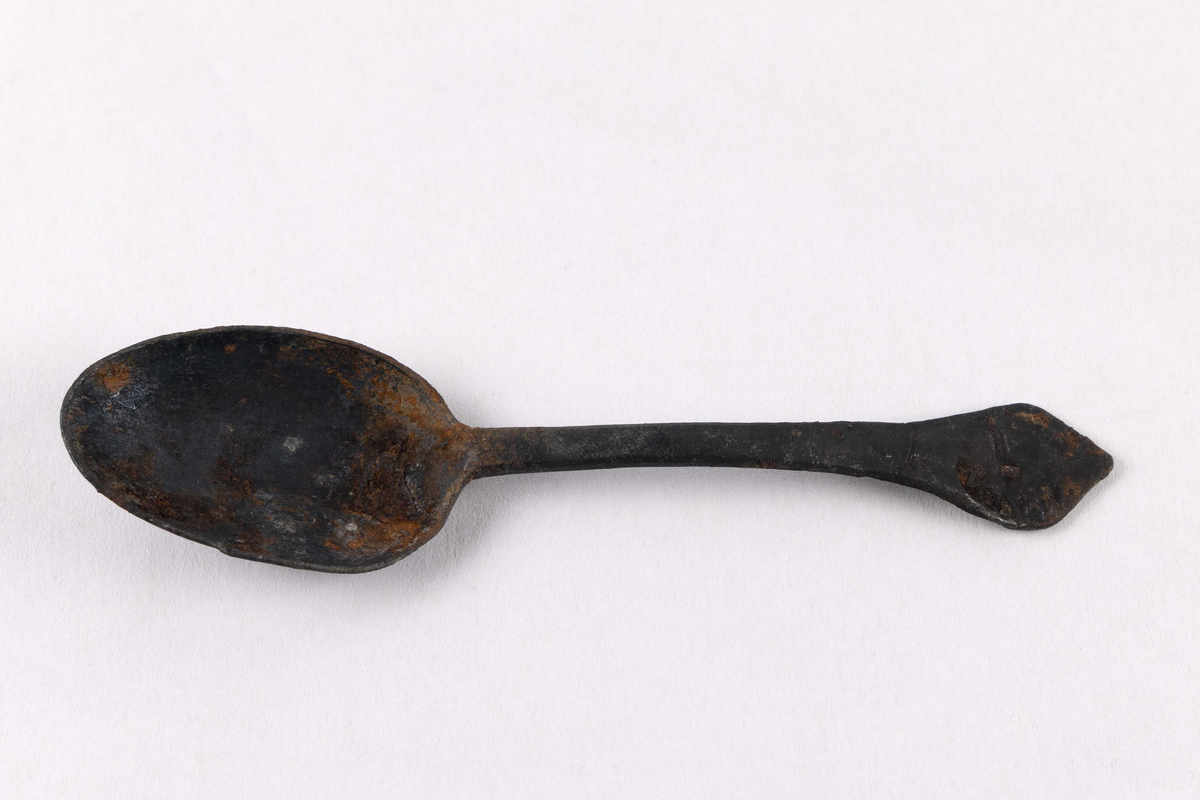 Komplett skje med hode og skaft funnet ved skipet AKERENDAM som forliste på Runde i 1725. Skaft enkelt dekorert, samt stempel på bakside av skaft.