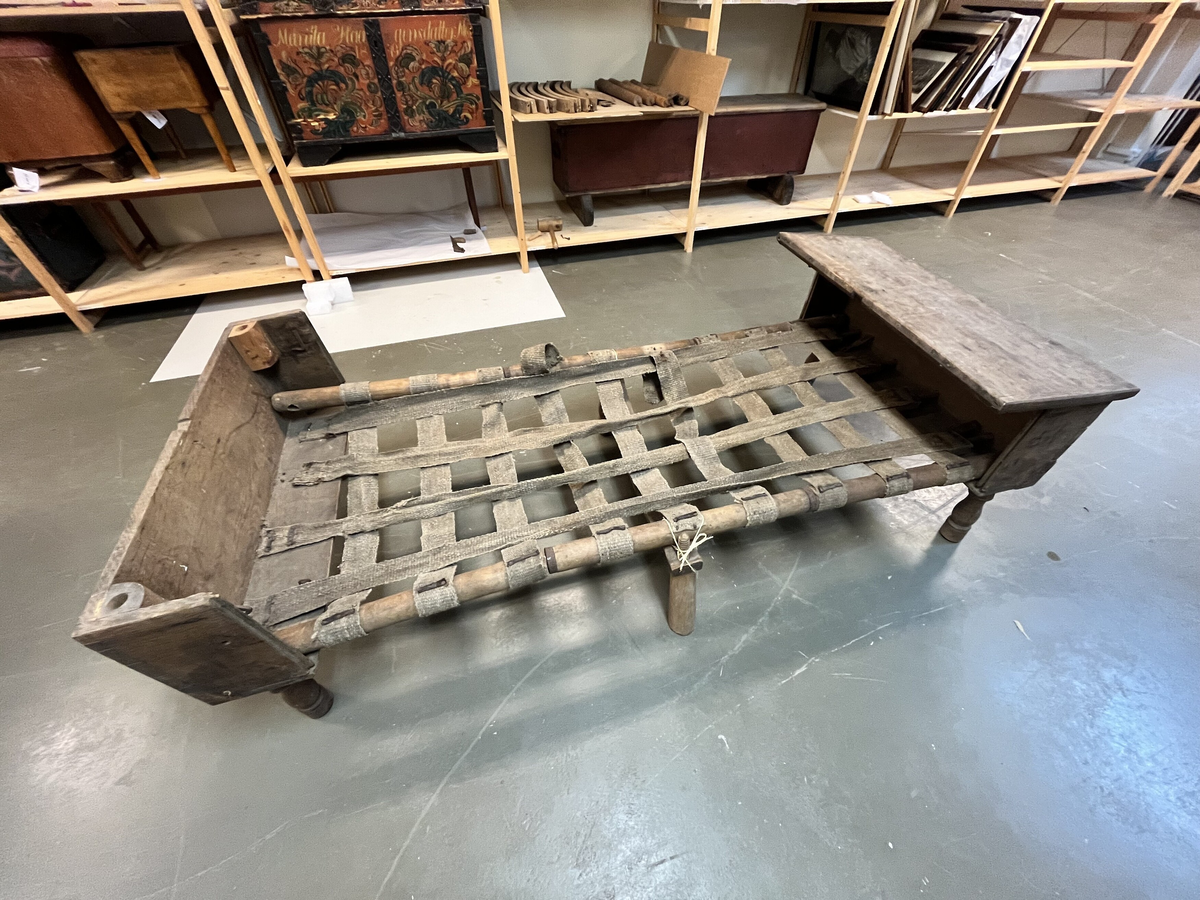 Form: Har form av ei "topseng".
1 topseng i kasse.

En slags fæltseng i form av en topseng. Kassen av eketræ. Umalt. Kassen har hat laas, der nu mangler.

