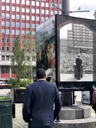 Åpningen av utstillingen "Pølserog politikk" på Youngstorget, et samarbeid mellom Arbark, Bymiljøetaten og Folkets hjørne 2.juni 2025. Mann som ser på bilde: Lo sekretariatets 1.sekretær Fawsi Adem.