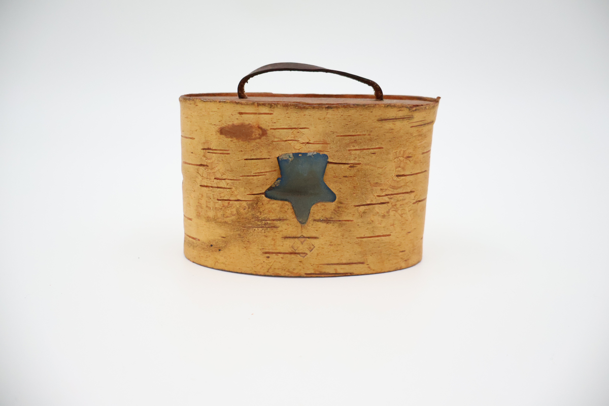 Oval näverburk med lock. Liten. Nävret är tampat stående. Nävret är pålimmat på bottenplattan i trä. Även locket består av trä och har ett handtag i läder. Läderremmen är trädd genom två hål i locket och på lockets insida avslutas remmen med två knutar. Burken har utstansade dekorationer i form av solfjädrar, romber, blommor och en stjärna. Burken består av två lager näver och emellan nävret är blått tyg inlagt som skymtar fram i stjärnan och blommorna. Burken är i relativt gott skick.