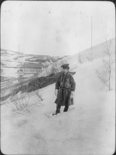En mann kledt i pesk står i en bakke ovenfor jernbanesporet i Bjørnevatn.