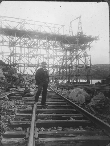 En av broene over lastekaia under bygging, en mann står i forgrunnen på jernbanesporet, A/S Sydvaranger.
